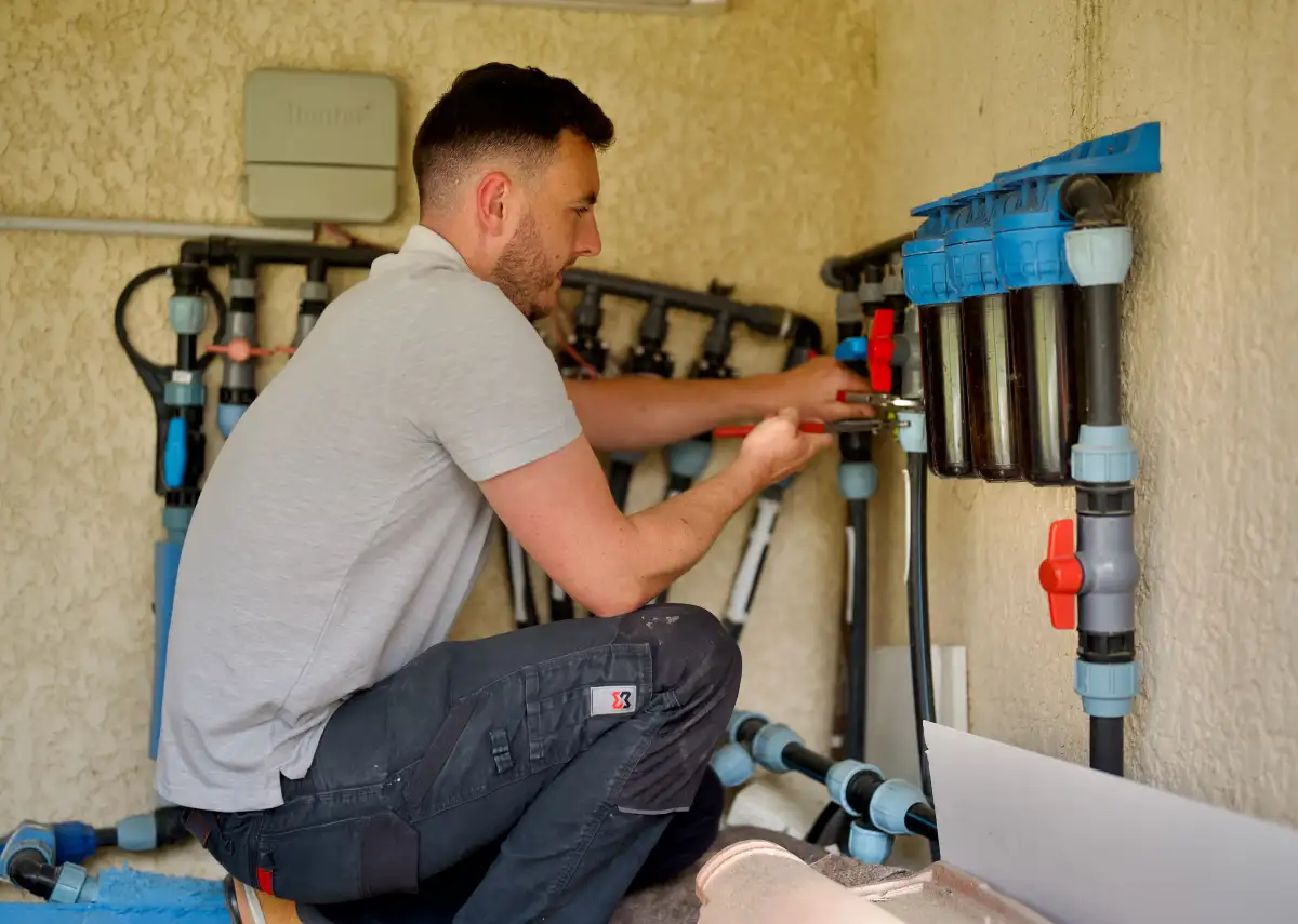 a man kneeling on the ground working on a water filter system